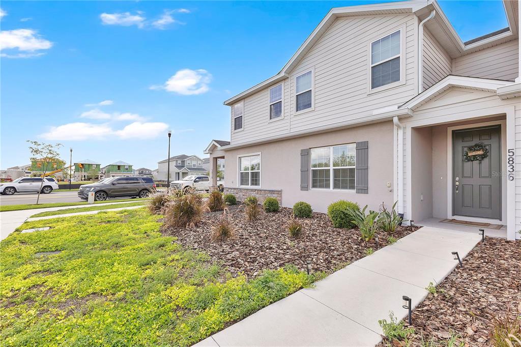 A two-story house with light-colored siding, a gray front door, and a landscaped front yard — 5836 FRESHWATER CANYON DRIVE, ST CLOUD, FL