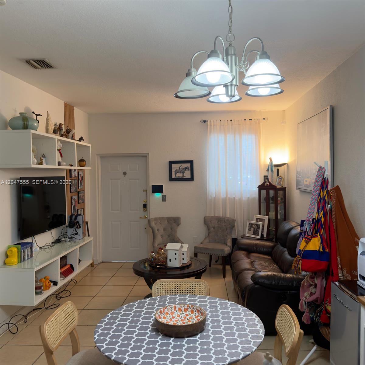 A living and dining area features tile floors, a chandelier, a television unit, and furniture — 17820 NW 73rd Ave # 1, Hialeah FL 33015, HIALEAH, FL