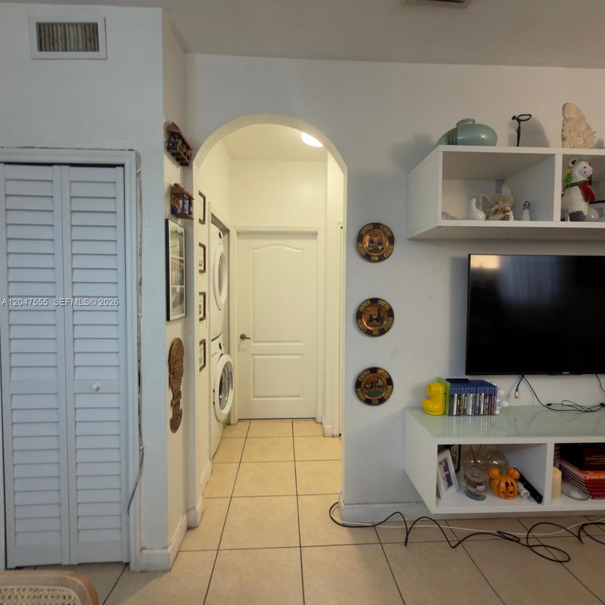 A living room features a tiled floor, an arched entryway to a laundry area, and shelving — 17820 NW 73rd Ave # 1, Hialeah FL 33015, HIALEAH, FL