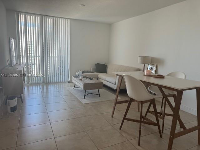 A living room with tile floors, a white sofa, a coffee table, and a dining set — 1250 S Miami Ave # 1607, Miami FL 33130, MIAMI, FL