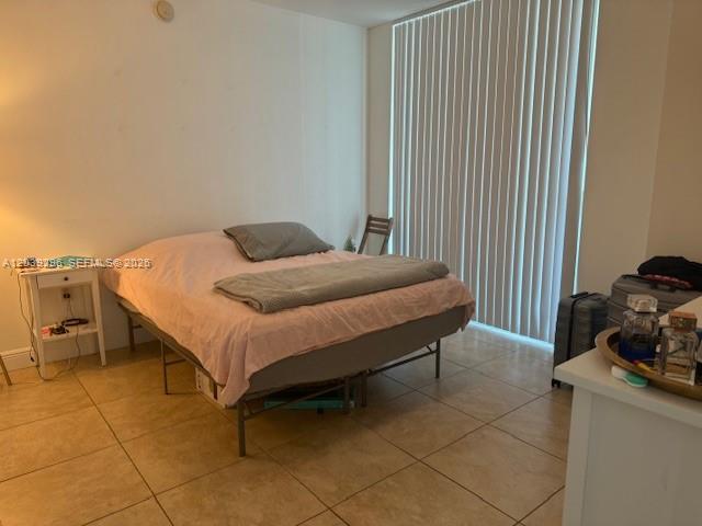 A bedroom features a bed with a pink cover, a nightstand, and vertical window blinds — 1250 S Miami Ave # 1607, Miami FL 33130, MIAMI, FL