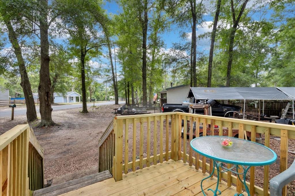 A wooden deck with a small table overlooks a wooded yard and a parked truck — 901 NE 11TH AVENUE, TRENTON, FL