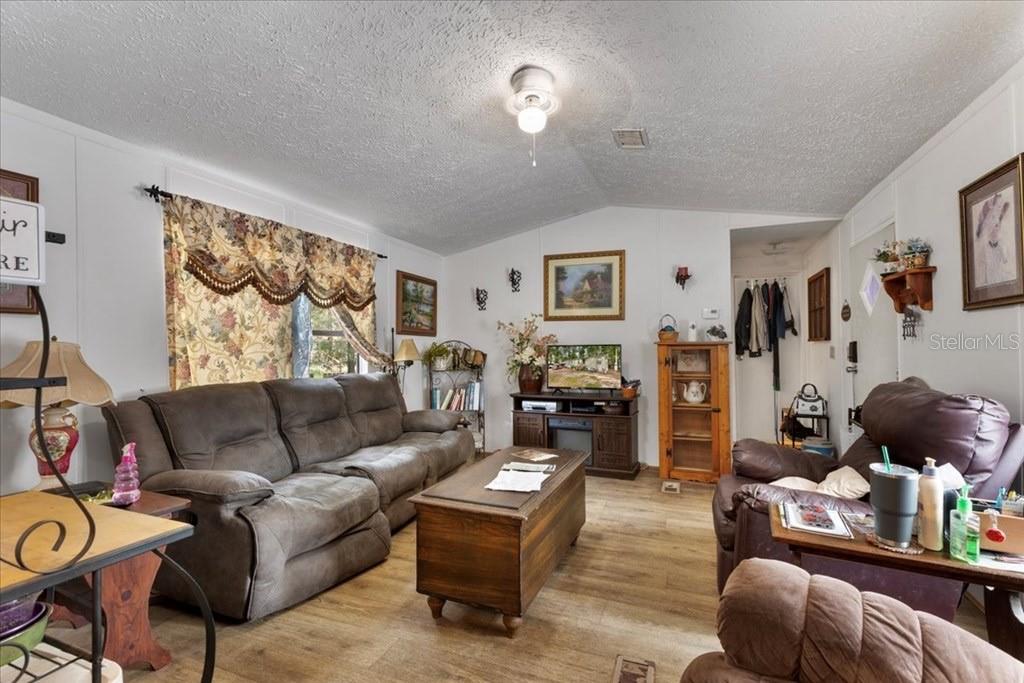 A living room features a brown sofa, a wooden coffee table, and light wood flooring — 901 NE 11TH AVENUE, TRENTON, FL