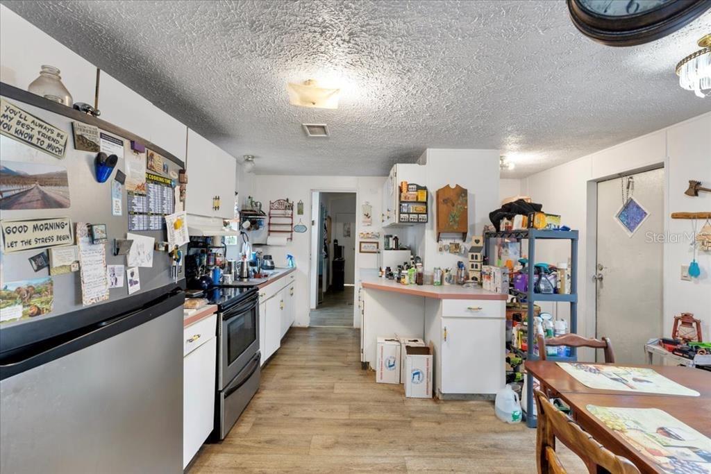 A kitchen features white cabinets, stainless steel appliances, and wood-look flooring — 901 NE 11TH AVENUE, TRENTON, FL