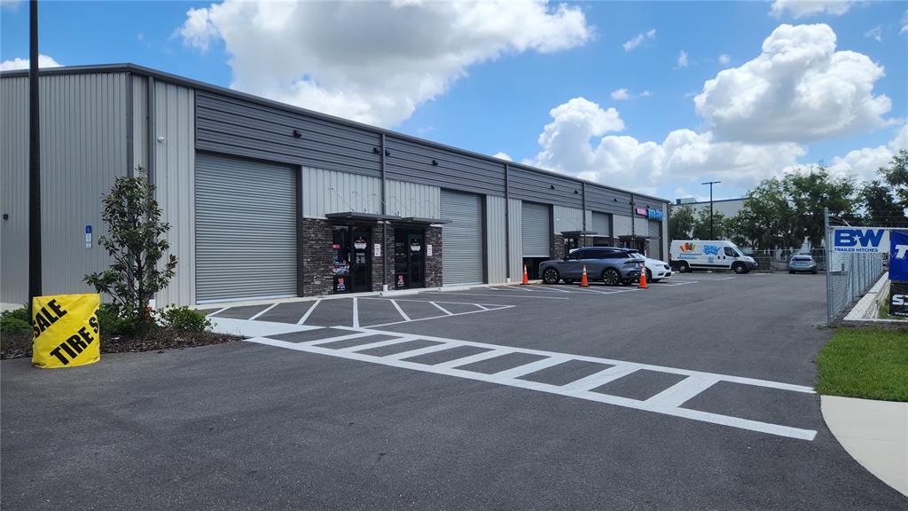 A modern industrial building with metal siding, roll-up doors, and a paved parking lot — 1800 CORPORATE CENTER LANE, PLANT CITY, FL