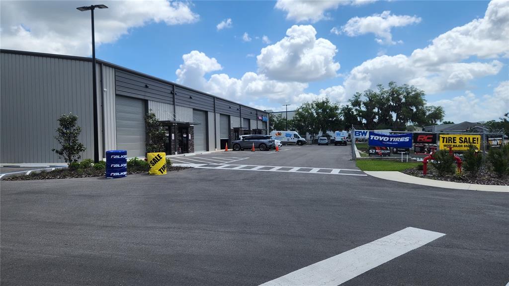 A commercial building exterior features a paved parking lot with tire sale signage — 1800 CORPORATE CENTER LANE, PLANT CITY, FL