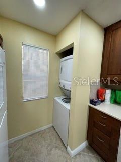 A laundry closet features a stacked washer and dryer next to a window and cabinets — 650 YOUNGSTOWN PARKWAY UNIT 215, ALTAMONTE SPRINGS, FL