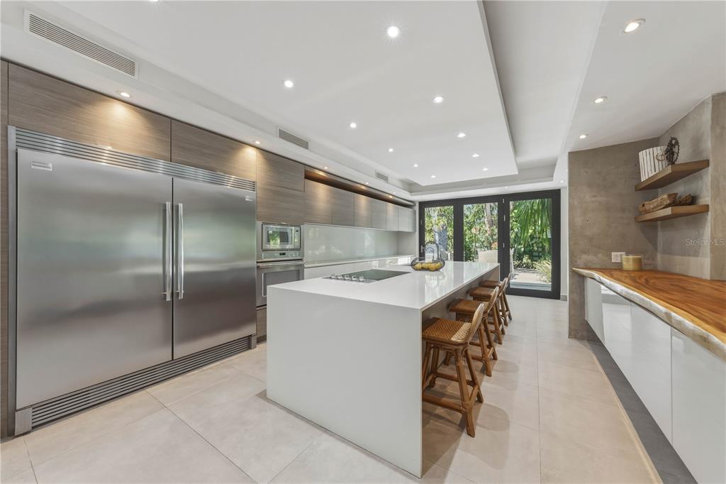 A modern kitchen features a large white island, stainless steel appliances, and wood cabinetry — 29 DORADO BEACH EAST, DORADO, PR