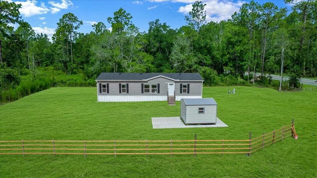 A single-story manufactured home sits on a large grassy lot with a storage shed — 8500 E HIGHWAY 318, CITRA, FL