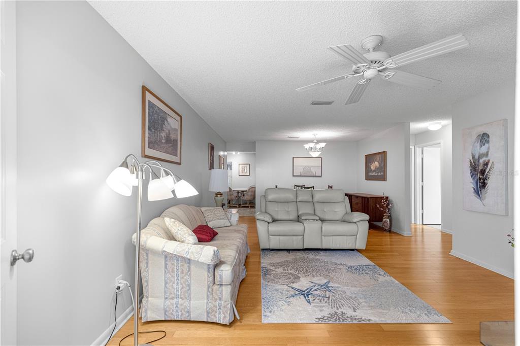 A living room features a patterned sofa, a light-colored loveseat, and a coastal-themed area rug — 8785 SW 91ST STREET UNIT D, OCALA, FL