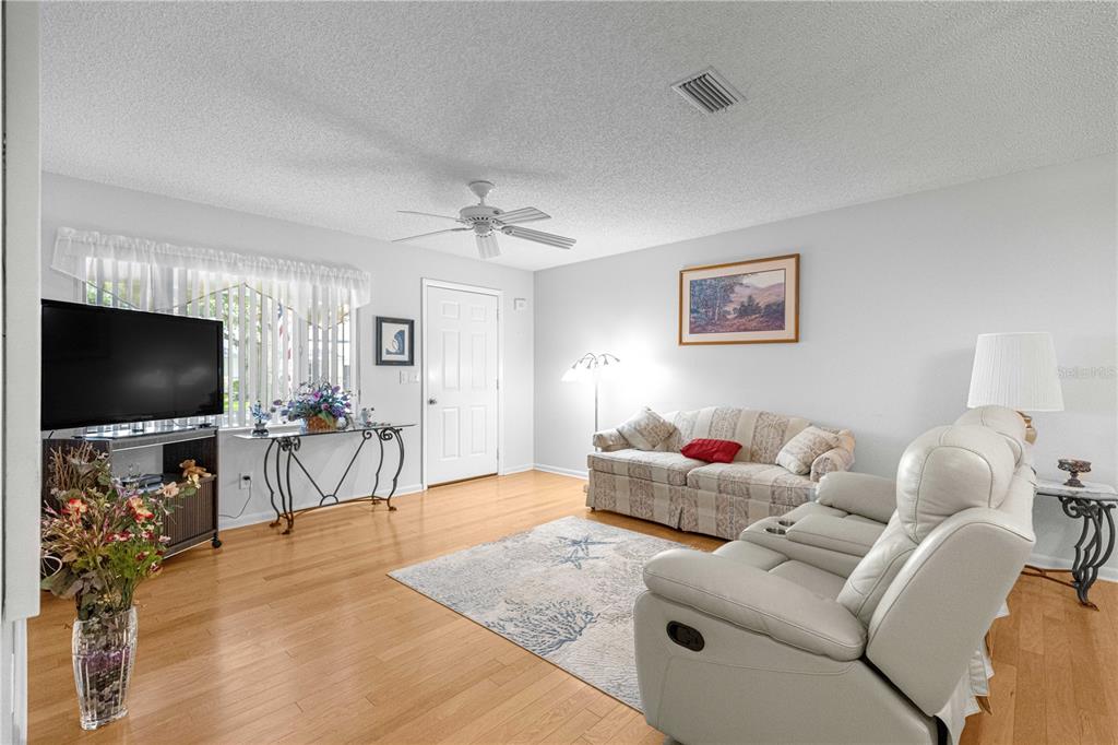 A living room features hardwood floors, a ceiling fan, a sofa, and a recliner — 8785 SW 91ST STREET UNIT D, OCALA, FL