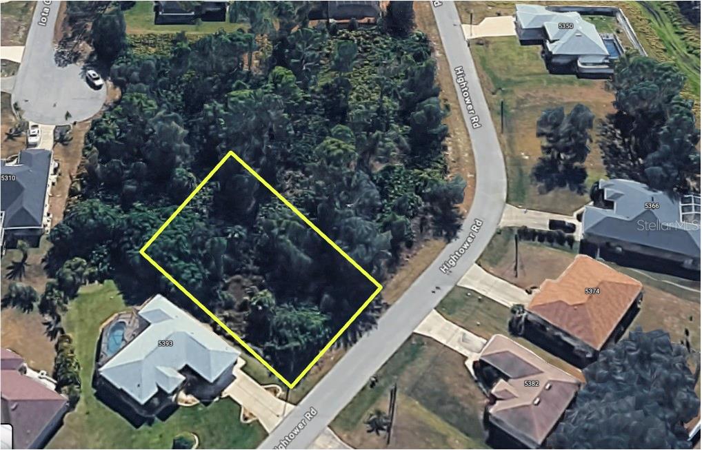 An aerial view shows a vacant, wooded residential lot outlined in yellow along a road — HIGHTOWER ROAD, NORTH PORT, FL