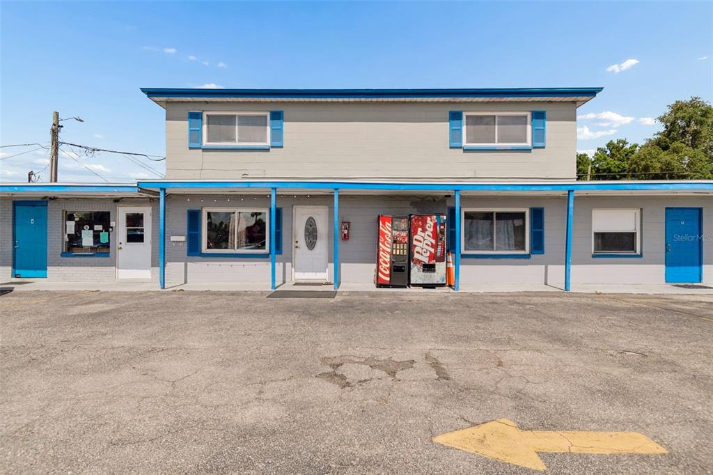 A two-story gray building with blue trim, vending machines, and a paved parking lot — 6409 S DALE MABRY HIGHWAY, TAMPA, FL