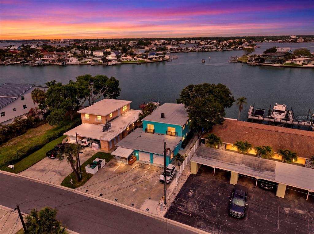 An aerial view shows two waterfront houses with driveways and a boat dock at sunset — 2311 BAY BOULEVARD, INDIAN ROCKS BEACH, FL
