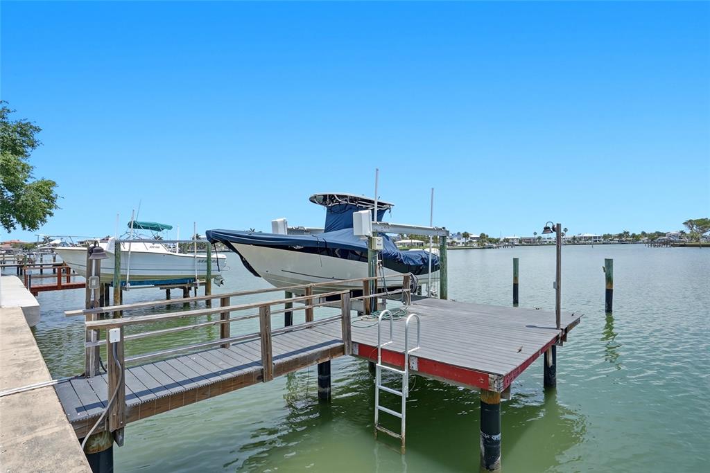 A wooden dock extends into the water with two boats secured on lifts — 2311 BAY BOULEVARD, INDIAN ROCKS BEACH, FL