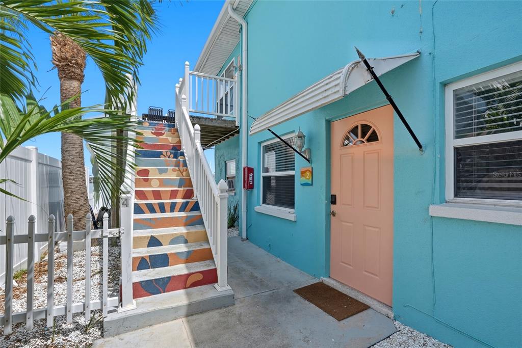 An exterior view of a turquoise building with a peach door and painted outdoor stairs — 2311 BAY BOULEVARD, INDIAN ROCKS BEACH, FL