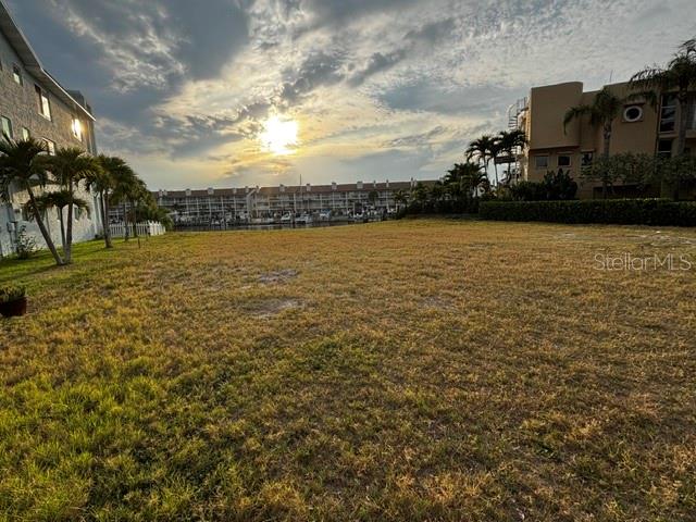 A vacant grassy lot sits between two multi-story buildings near a waterfront marina — 1 1ST AVENUE S, TIERRA VERDE, FL