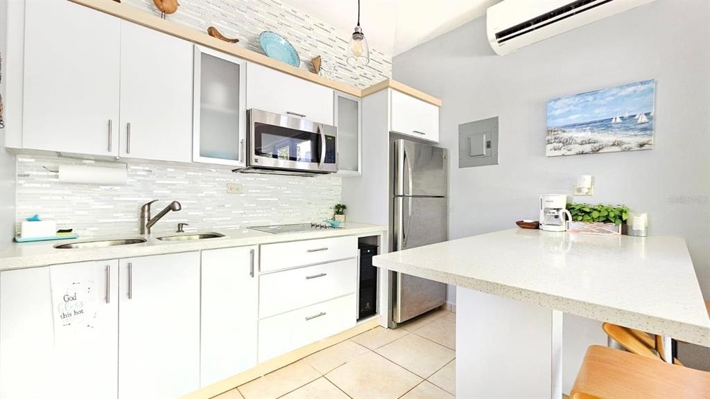 A kitchen features white cabinetry, stainless steel appliances, a tiled backsplash, and a peninsula counter — Carr. PR 307 km 8.5 BOQUERÓN BAY SIDE INC, CABO ROJO, PR