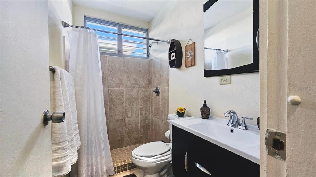 A small bathroom features a tiled shower, a white toilet, and a dark vanity cabinet — Carr. PR 307 km 8.5 BOQUERÓN BAY SIDE INC, CABO ROJO, PR