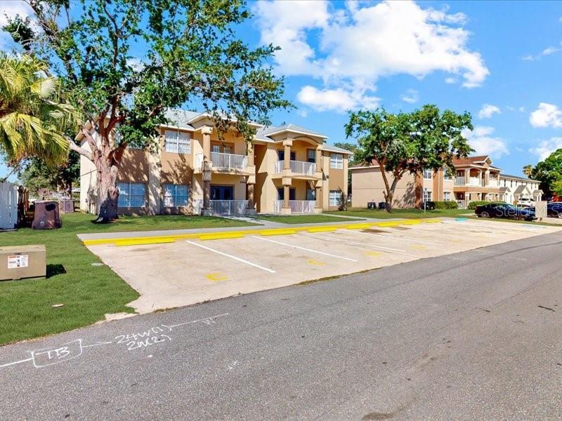 An exterior view of a multi-story apartment building with a paved parking lot in front — 206 MAJORS LANE UNIT B, KISSIMMEE, FL