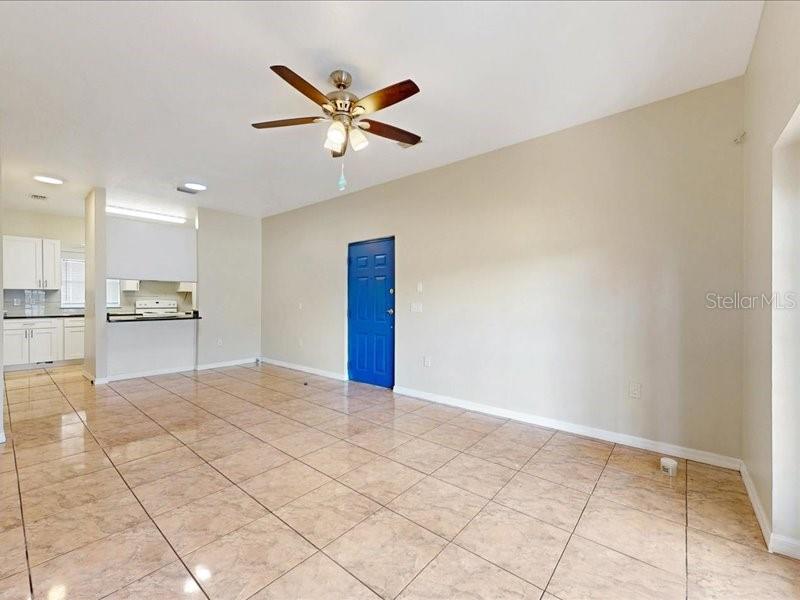 An open-concept living area features light-colored tile flooring, a ceiling fan, and a blue door — 206 MAJORS LANE UNIT B, KISSIMMEE, FL
