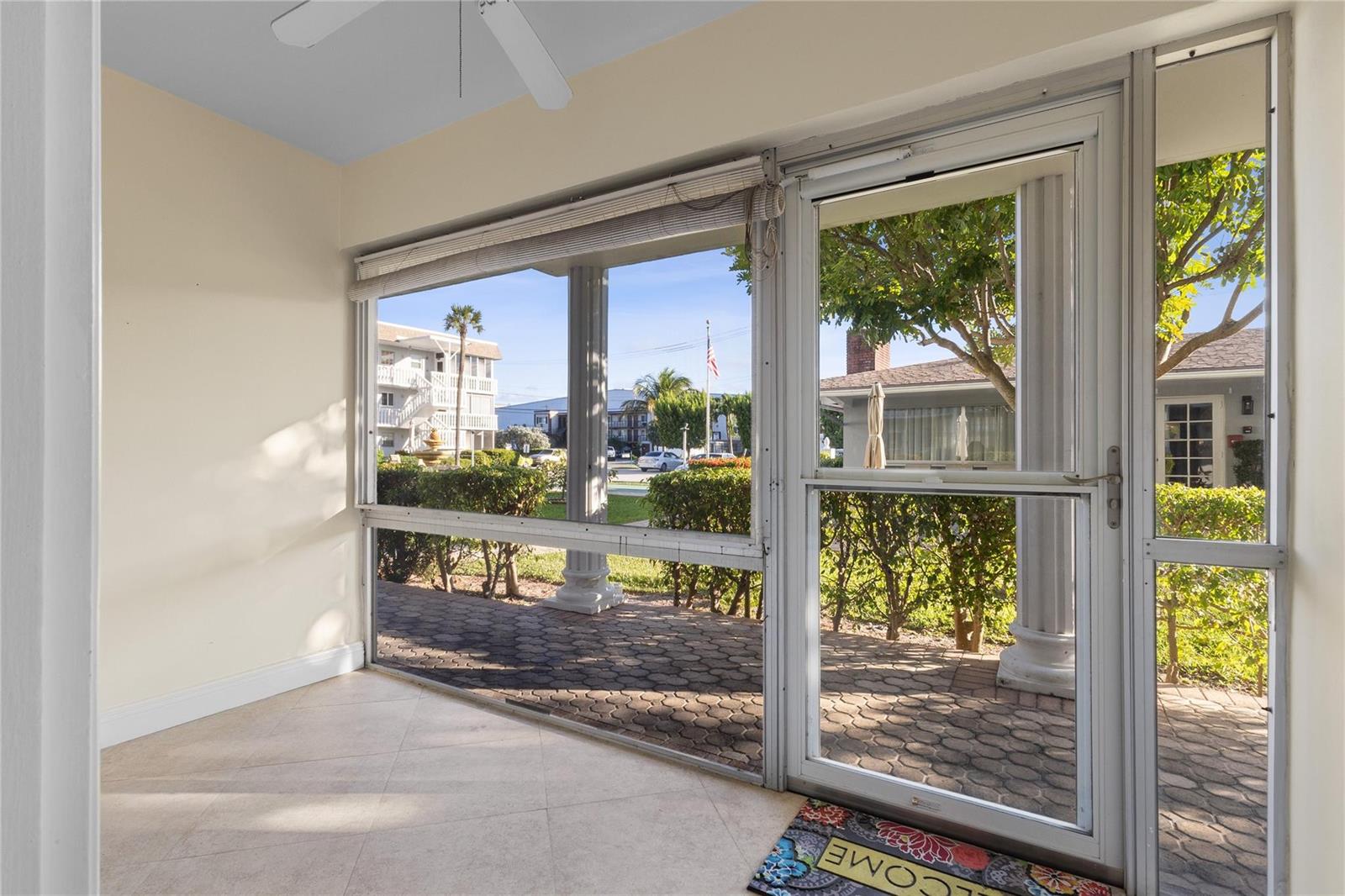 A sunroom features tile flooring, a ceiling fan, and large windows overlooking a paved patio — 1965 SE 5th Court # 104, Pompano Beach FL 33060, POMPANO BEACH, FL