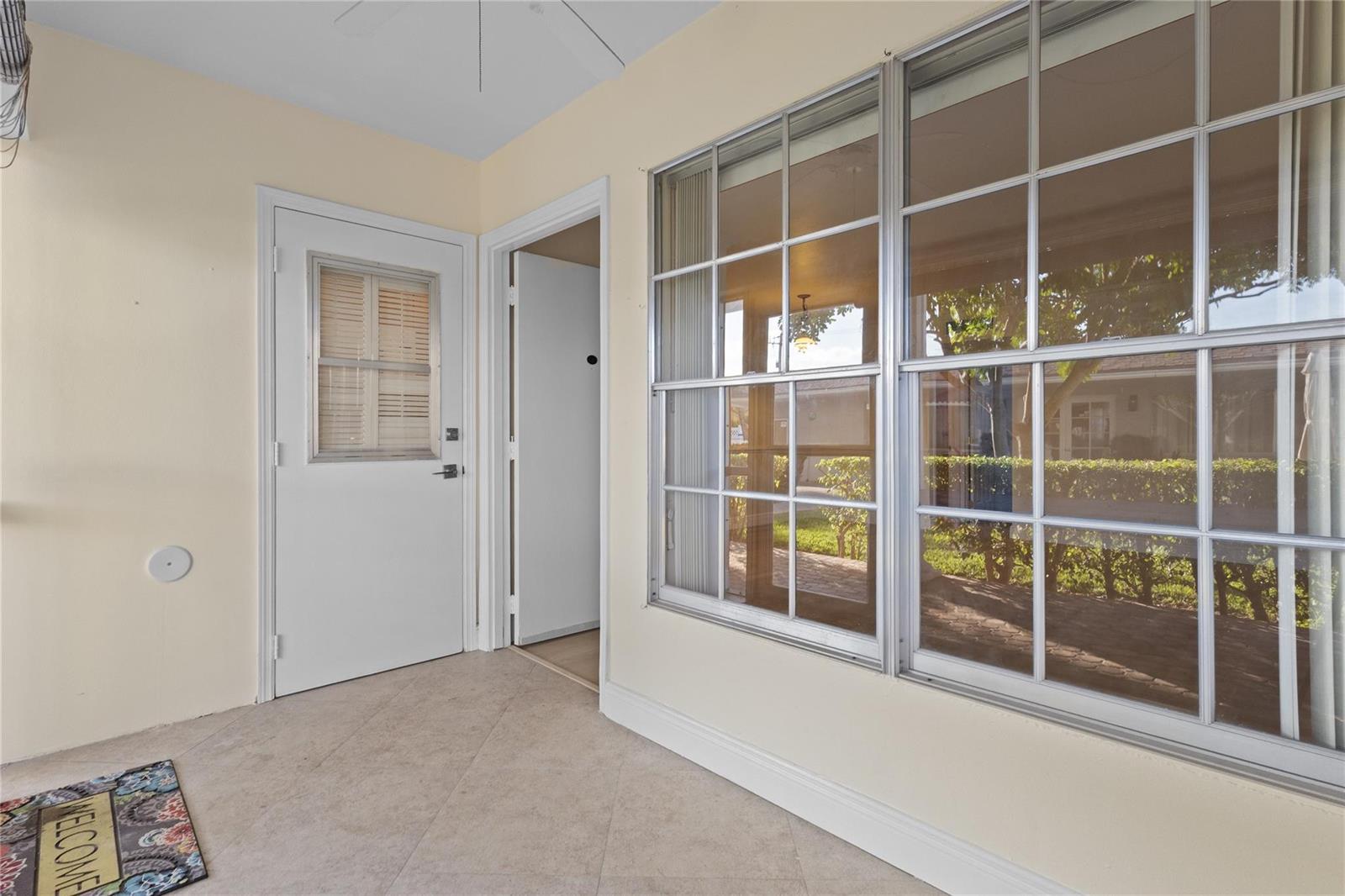 A covered patio features tiled flooring, a white door, and large windows looking outside — 1965 SE 5th Court # 104, Pompano Beach FL 33060, POMPANO BEACH, FL