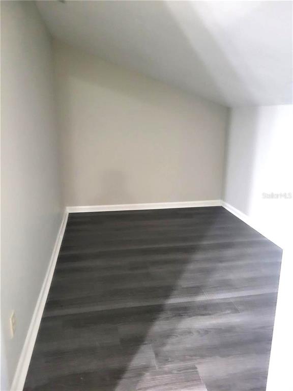An empty room features light gray walls, white trim, and dark wood-look flooring — 3545 E FORT KING STREET UNIT 257, OCALA, FL
