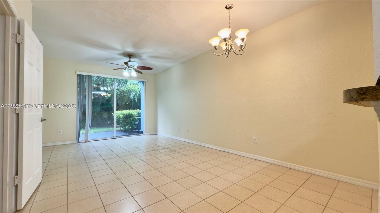 An empty room features beige tile flooring, a ceiling fan, and a sliding glass door — 1918 Alamanda Way, Riviera Beach FL 33404, RIVIERA BEACH, FL