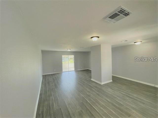 An open-concept room features light gray walls, wood-look flooring, and a sliding glass door — 705 HARLAND COURT, KISSIMMEE, FL