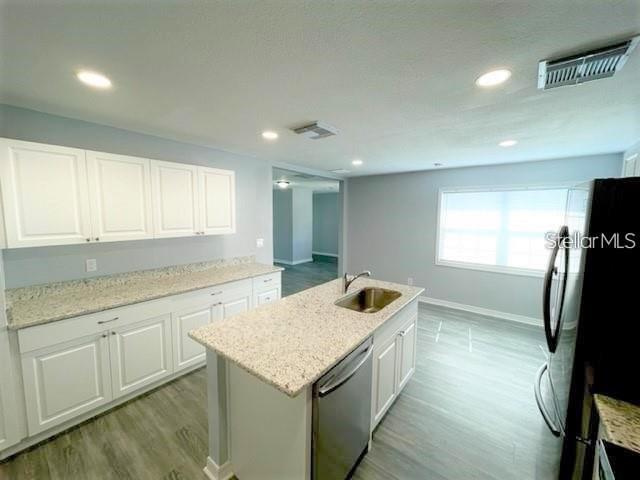 A kitchen features white cabinets, granite countertops, a center island, and light-colored wood flooring — 705 HARLAND COURT, KISSIMMEE, FL