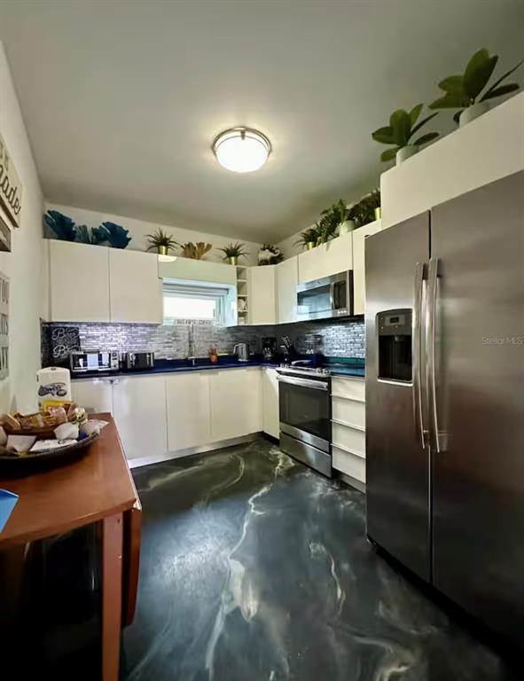 A kitchen features white cabinetry, stainless steel appliances, and a dark, marbled epoxy floor — 13 CALLE VILLA INTERNACIONAL 2, SAN JUAN, PR