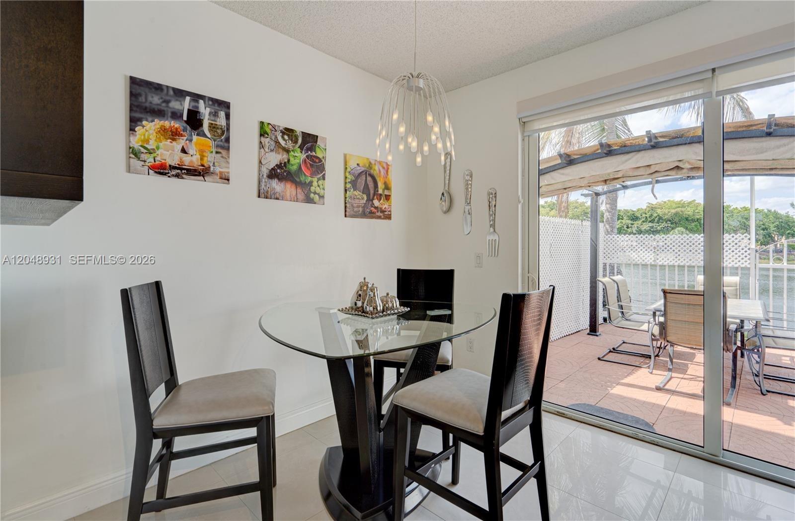A dining area features a glass table, dark chairs, wall art, and a sliding glass door — 8535 SW 152nd Ave # 204, Miami FL 33193, MIAMI, FL