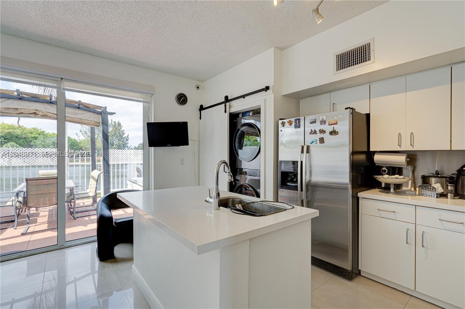 A kitchen features a white island with a sink, stainless steel appliances, and a laundry closet — 8535 SW 152nd Ave # 204, Miami FL 33193, MIAMI, FL