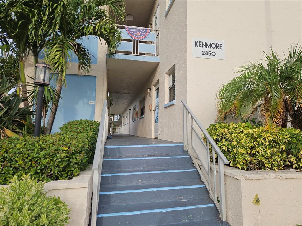 Exterior view of a multi-story apartment building with stairs leading to an open walkway — 2850 59TH STREET S UNIT 115, ST PETERSBURG, FL