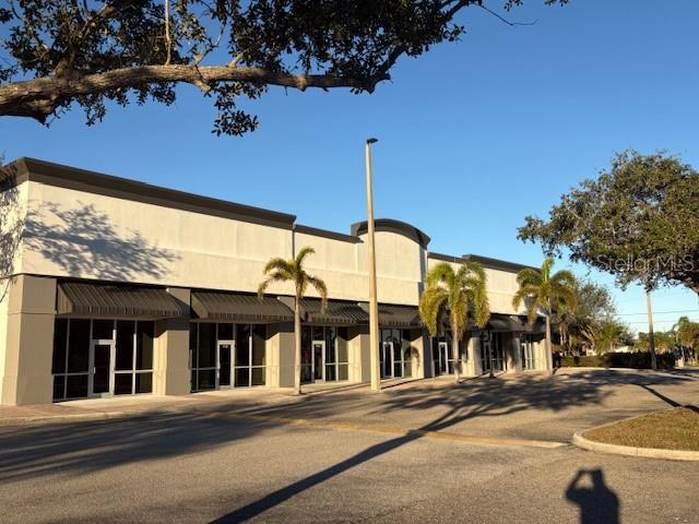 A single-story commercial strip mall building with glass storefronts and palm trees under a blue sky — 10169 TAMIAMI TRAIL UNIT 2125, PUNTA GORDA, FL