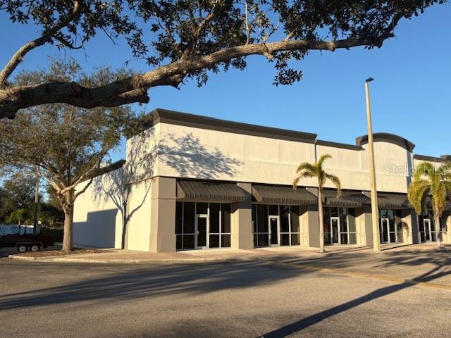 A single-story commercial building with a beige facade, dark awnings, and a parking lot — 10169 TAMIAMI TRAIL UNIT 2125, PUNTA GORDA, FL