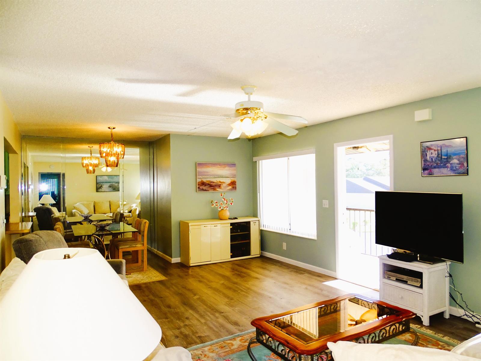 A living room with light green walls, wood-look flooring, a ceiling fan, and a television — 409 Pine Glen Lane # 2, FL 33463, FL
