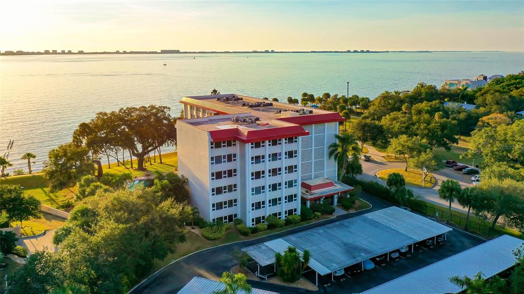 An aerial view shows a multi-story apartment building with a red roof near water — 1100 IMPERIAL DRIVE UNIT 108, SARASOTA, FL