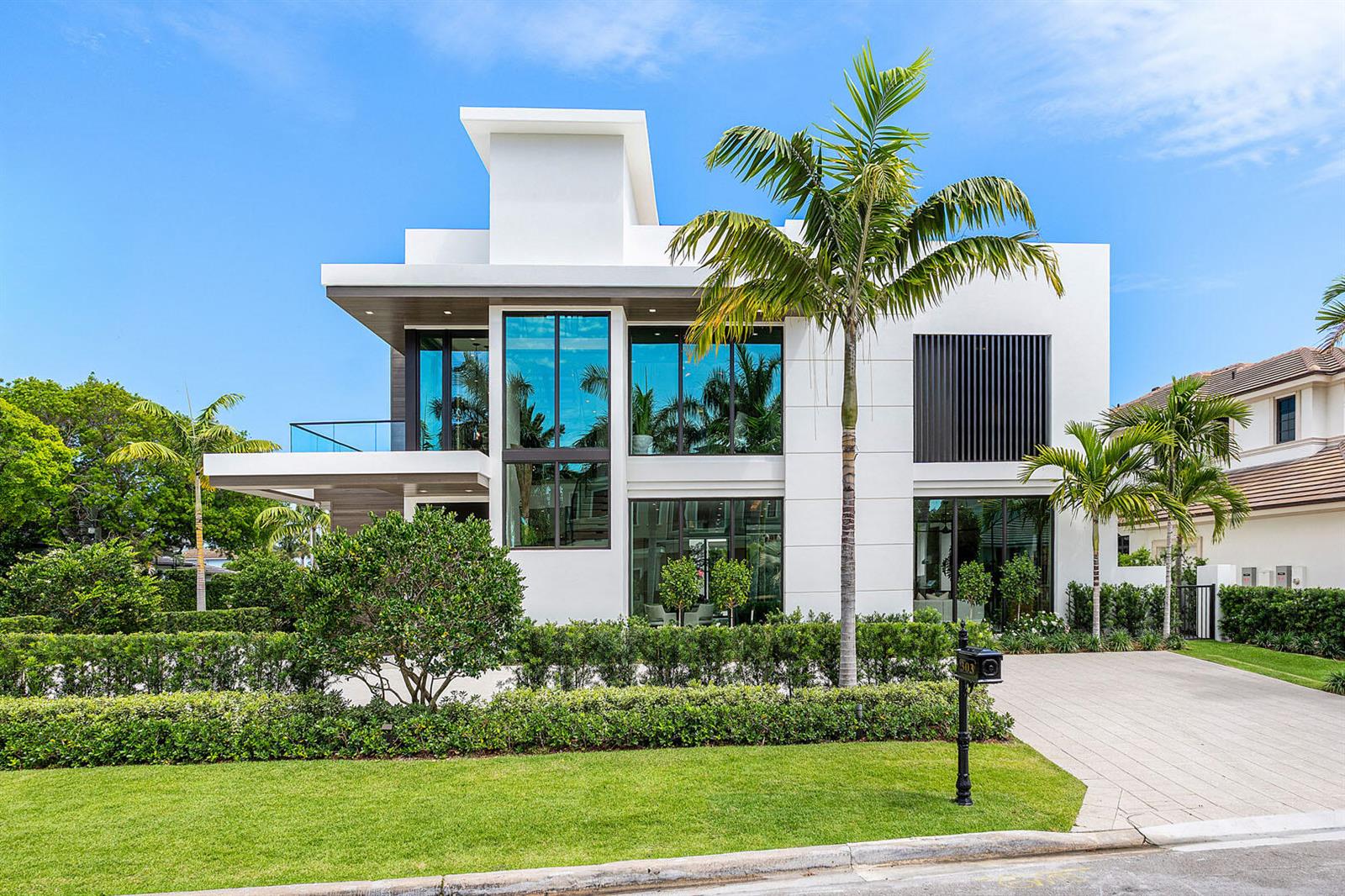 A modern two-story white house features large glass windows, a palm tree, and a paved driveway — 303 S Maya Palm Drive, Boca Raton FL 33432, BOCA RATON, FL