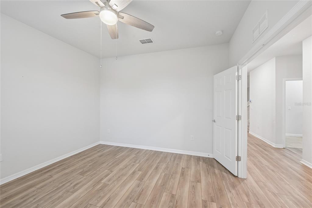 An empty bedroom features light wood-look flooring, white walls, and a ceiling fan — 11716 BRIGHTON KNOLL LOOP, RIVERVIEW, FL