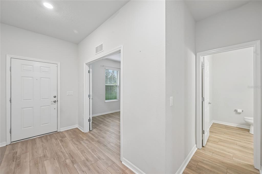 An interior view shows a hallway with wood-look flooring, a front door, and two doorways — 11716 BRIGHTON KNOLL LOOP, RIVERVIEW, FL