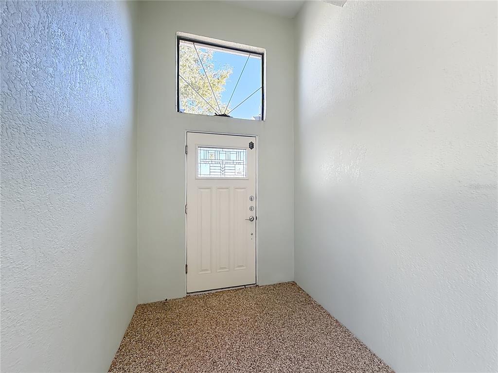An entryway features a white door with a glass insert, a transom window, and carpet — 5510 CELEBRATION WAY, LEESBURG, FL