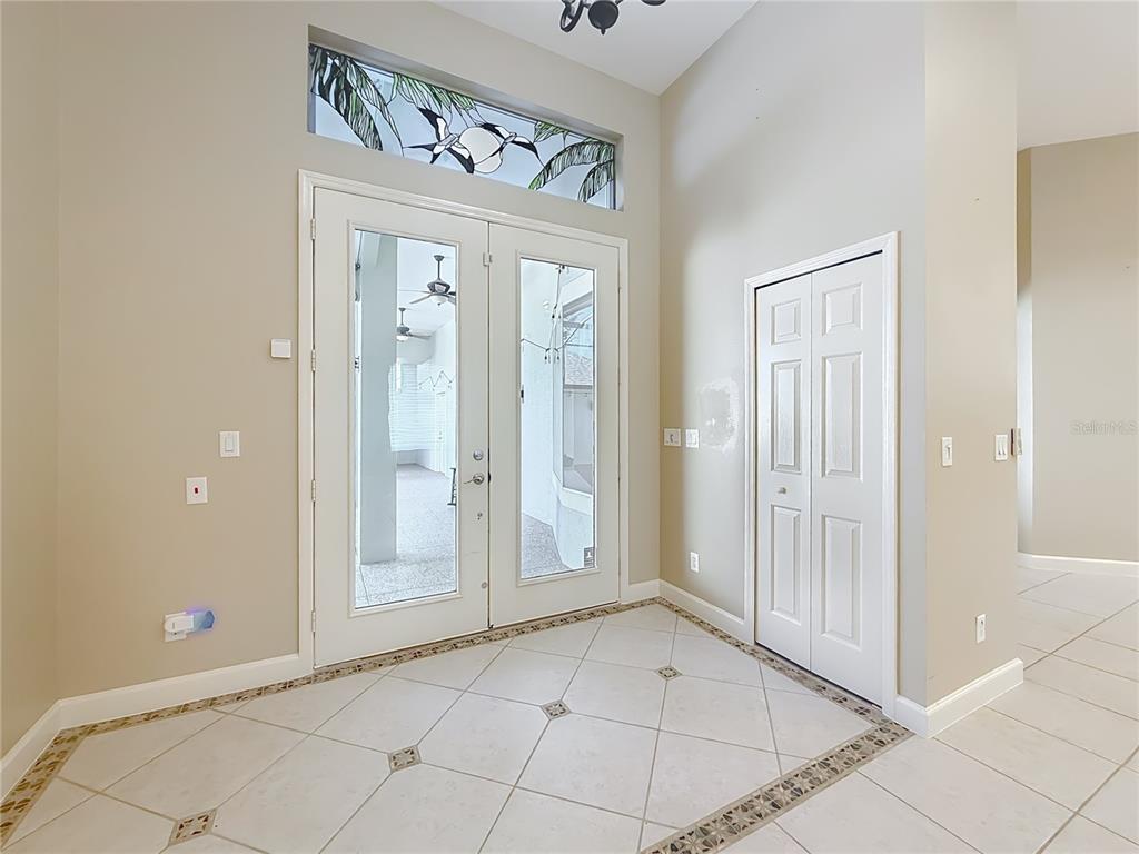 An entryway features double glass doors, a transom window, and light-colored tile flooring — 5510 CELEBRATION WAY, LEESBURG, FL