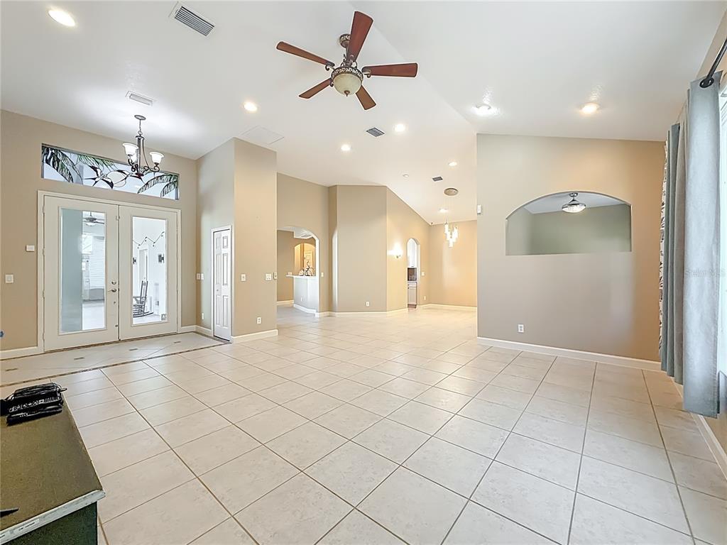 A spacious living room features light-colored tile flooring, vaulted ceilings, and an arched wall cutout — 5510 CELEBRATION WAY, LEESBURG, FL