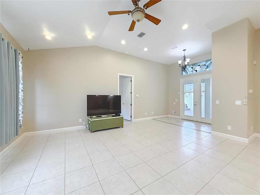 A living room features light-colored tile flooring, a ceiling fan, and double glass doors — 5510 CELEBRATION WAY, LEESBURG, FL