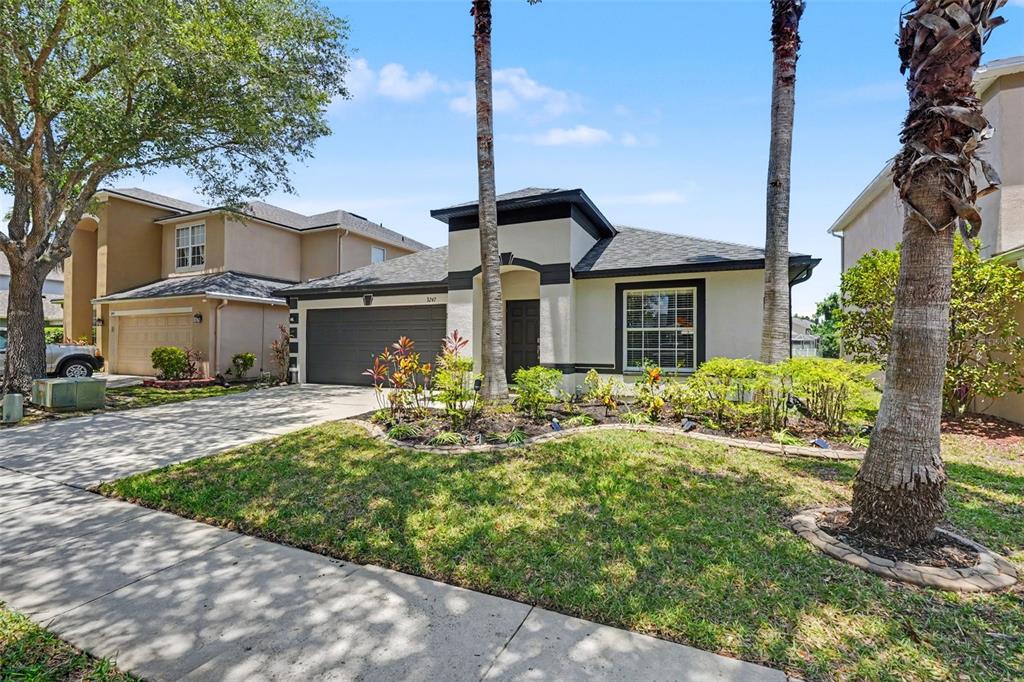 A single-story house with a beige stucco exterior, dark trim, and a two-car garage — 3247 DUNSTABLE DRIVE, LAND O LAKES, FL