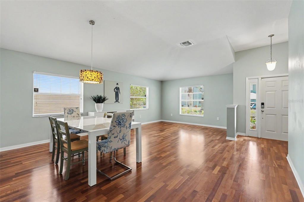 A dining area with a white table, patterned chairs, and hardwood floors near an entryway — 3247 DUNSTABLE DRIVE, LAND O LAKES, FL
