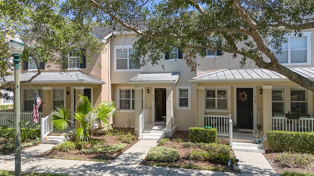 A row of three attached townhouses with tan stucco exteriors and metal porch roofs — 9135 CARDINAL MEADOW TRAIL, ORLANDO, FL