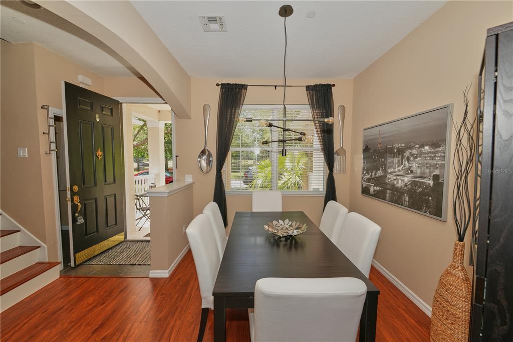 A dining room features a dark wood table, white chairs, and large wall-mounted utensils — 9135 CARDINAL MEADOW TRAIL, ORLANDO, FL